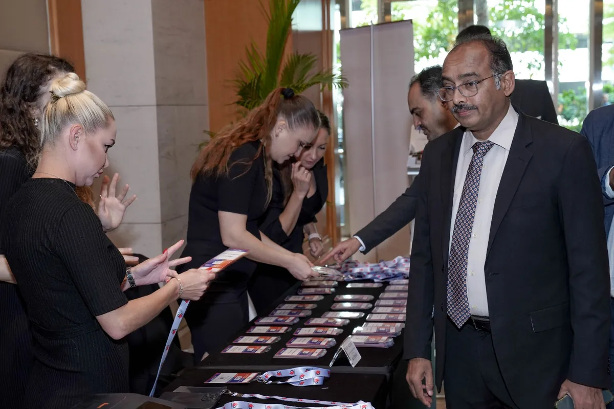 A suited delegate collects materials from a registration table at an industry event.