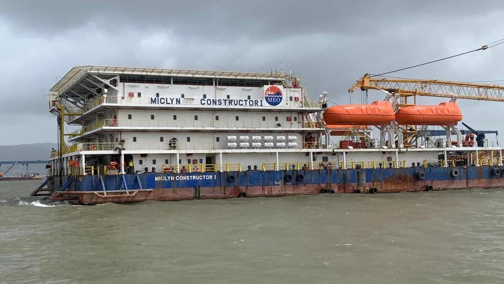 The Miclyn Constructor I accommodation block, orange lifeboats and deck are seen broadside on grey water.