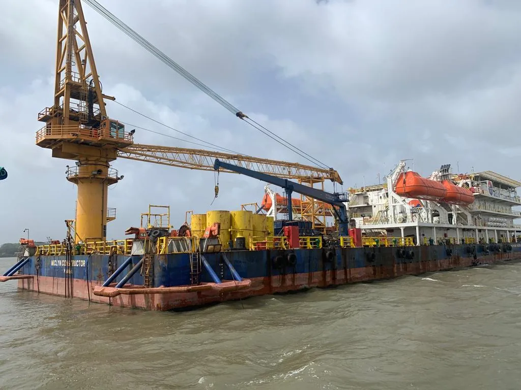 An oblique view shows a vessel working deck, yellow crane, orange lifeboat and white accommodation block.