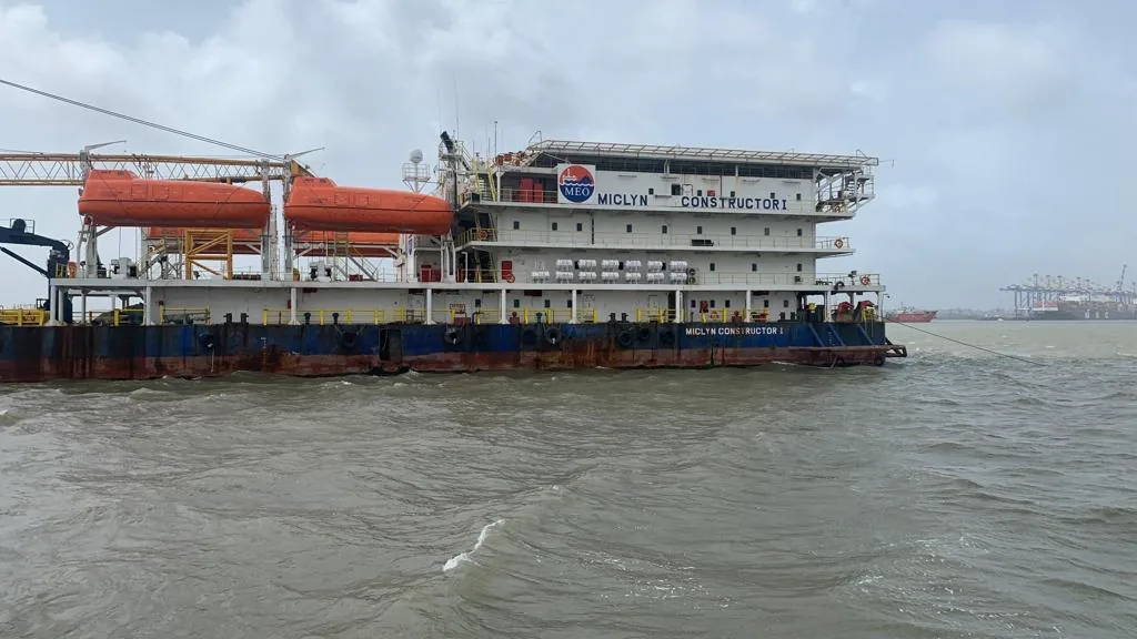 A crane vessel with orange lifeboats and a white accommodation block sits on grey, rippled water.