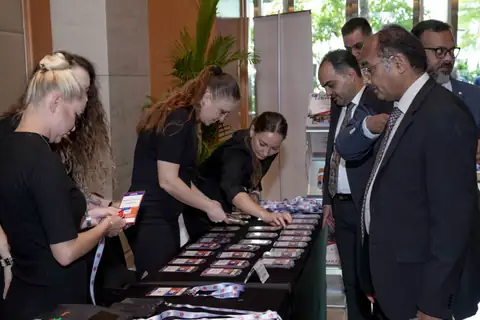 Delegates check in while event staff arrange name badges across a registration table.