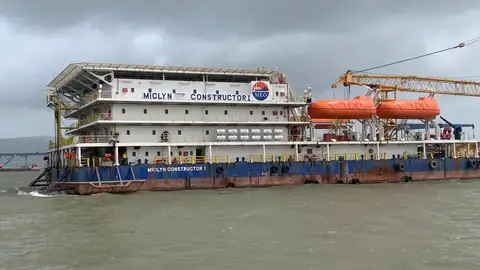 The Miclyn Constructor I accommodation block, orange lifeboats and deck are seen broadside on grey water.